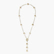 Gold-plated lariat necklace with baroque pearls and textured caps on cream background, showing adjustable Y-shaped design.