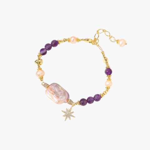 Gold-plated bracelet with baroque pearl centerpiece, amethyst beads, and crystal star charm on white background.
