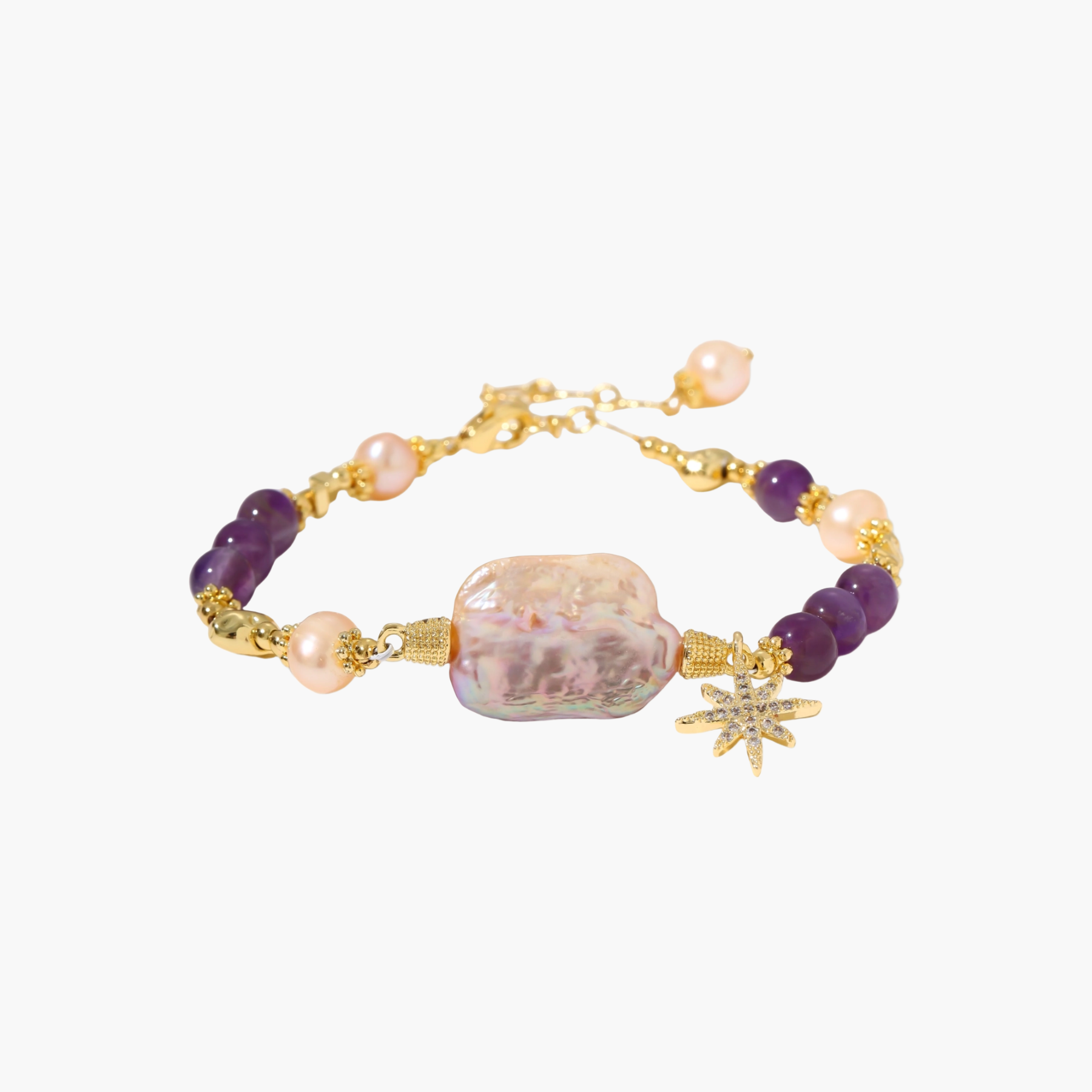 Gold-plated bracelet with baroque pearl centerpiece, amethyst beads, and crystal star charm on white background.