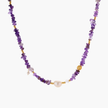 Beaded necklace with purple amethyst chips, freshwater pearls, and gold accents on white background.