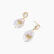 Gold-plated drop earrings with iridescent baroque pearls and crystal flower accents on cream background