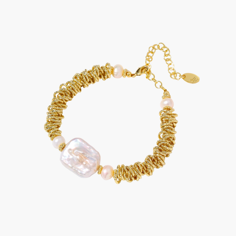 18k gold-plated bracelet with textured wave segments, baroque pearl centerpiece, and round freshwater pearls on cream background