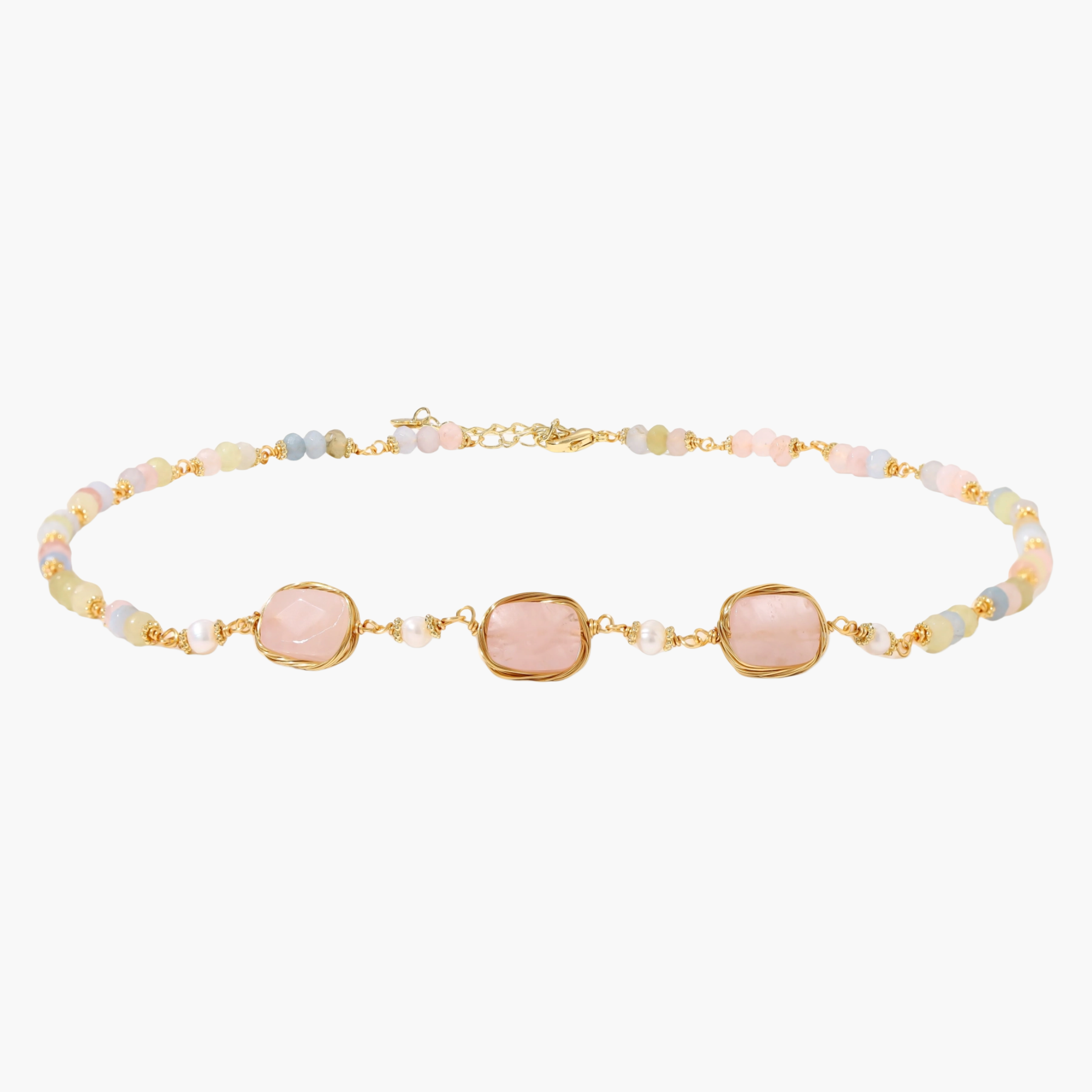 Gold necklace with three rose quartz stones, multicolor pastel beads, and pearl accents on white background.