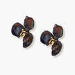 Dark iridescent baroque pearls arranged in flower pattern with 18K gold-plated center on cream background.