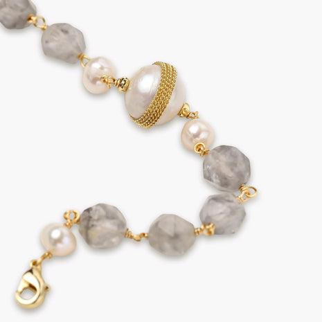 Bracelet with cloudy quartz beads, freshwater pearls, and gold-wrapped baroque pearl centerpiece on white background.
