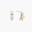 14K gold-plated curved stud earrings with three white freshwater pearls aligned vertically on cream background