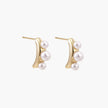 14K gold-plated curved stud earrings with three white freshwater pearls aligned vertically on cream background