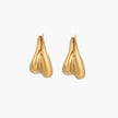 Pair of sculptural gold stud earrings with twisted organic forms on cream background
