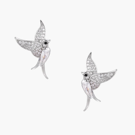 Pair of white gold-plated hummingbird stud earrings with pavé zirconia stones and teardrop crystal bodies on cream background