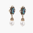 Ornate gold-plated earrings with iridescent abalone shell, crystals, blue stones, and white pearl drops on cream background.