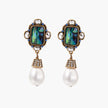Ornate gold-plated earrings with iridescent abalone shell, crystals, blue stones, and white pearl drops on cream background.