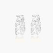 White gold plated sculptural hoop earrings with organic wavy edges and reflective metallic finish on cream background