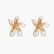 White enamel tropical flower earrings with sculptural gold-plated center and organic petal design on cream background