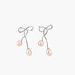 Rhodium-plated silver earrings with organic vine curves and two peachy freshwater pearls on cream background