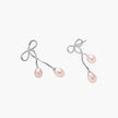 Rhodium-plated silver earrings with organic vine curves and two peachy freshwater pearls on cream background