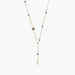Y-shaped gold-plated necklace with white and gray freshwater pearls on cream background, showing adjustable drop design.