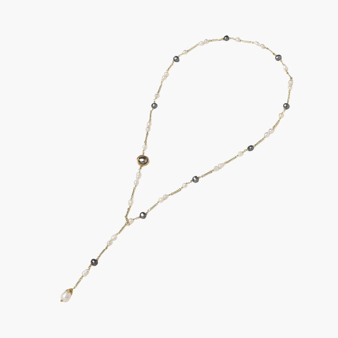 Y-shaped gold-plated necklace with white and gray freshwater pearls on cream background, showing adjustable drop design.