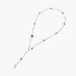 Y-shaped gold-plated necklace with white and gray freshwater pearls on cream background, showing adjustable drop design.