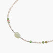 Delicate pearl necklace with pale green serpentine jade centerpiece and colorful agate beads on cream background