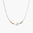 Delicate white beaded necklace with baroque pearl center, gold accents, and coral and aqua gemstones on cream background.