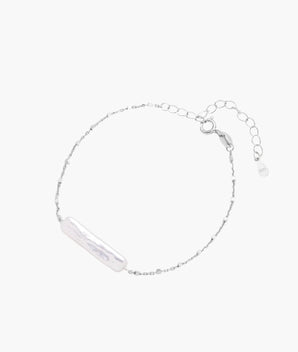 Minimalist bracelet with iridescent baroque pearl on rhodium-plated sterling silver chain against cream background