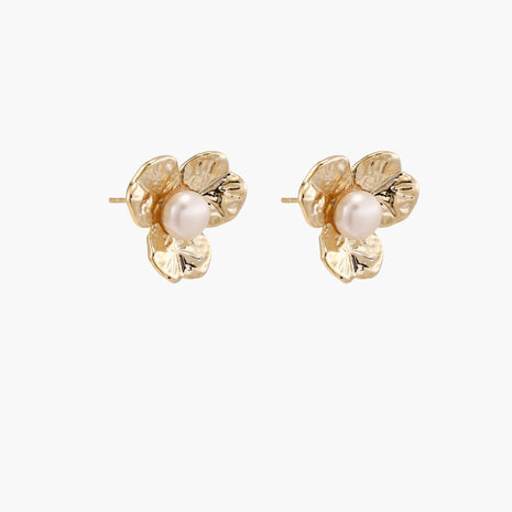 Gold-plated flower stud earrings with textured petals and centered freshwater pearl on beige background