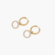 Gold-plated huggie hoop earrings with CZ-studded open circle charms on beige background