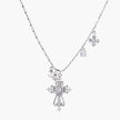 Ornate white gold-plated cross pendant with zirconia stones and pearl accents on adjustable silver chain against cream background