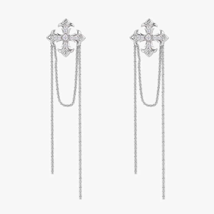 White gold plated baroque cross stud earrings with long cascading zirconia chains on cream background