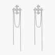 White gold plated baroque cross stud earrings with long cascading zirconia chains on cream background