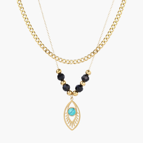 Layered gold necklace with turquoise evil eye pendant and black quartz beads on cream background