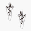 Silver dangle earrings with sculptural serpent coiled around cross shape and delicate chain accents on cream background