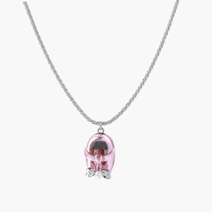 Translucent pink skull pendant with silver bow detail on delicate white gold plated chain against cream background