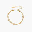 Three-strand gold-plated bracelet with clustered ball beads and adjustable clasp on cream background