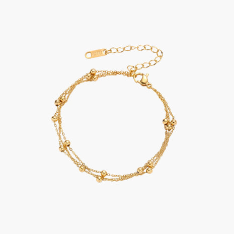 Three-strand gold-plated bracelet with clustered ball beads and adjustable clasp on cream background