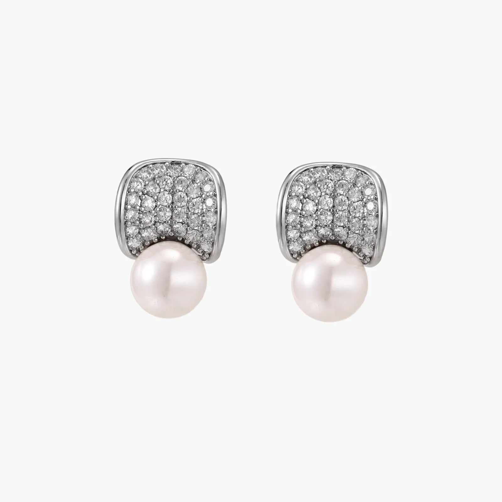 Curved pavé diamond studs in white gold-plated brass cradle lustrous freshwater pearls against cream background