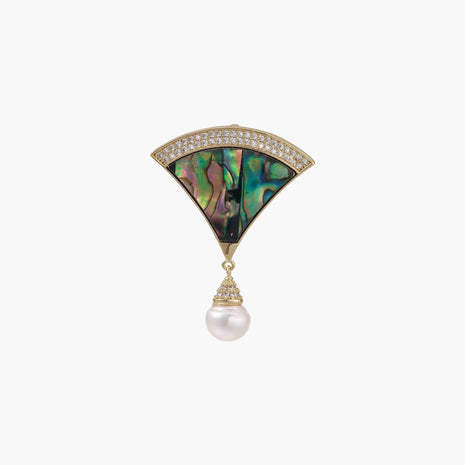 Gold fan-shaped brooch with iridescent abalone shell center, crystal border, and dangling white pearl on cream background