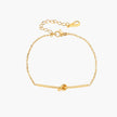 Delicate gold chain bracelet with minimalist bar and centered knot detail on cream background