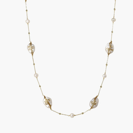 Long gold chain necklace with baroque pearls wrapped in leaf designs and small freshwater pearls spaced along the strand