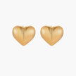 Gold heart-shaped stud earrings with parallel ridged texture on cream background