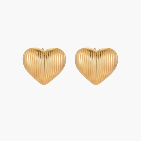 Gold heart-shaped stud earrings with parallel ridged texture on cream background