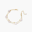 Double-strand gold bracelet with irregular baroque pearls and smooth freshwater pearls on cream background.