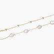 Double-strand gold bracelet with irregular baroque pearls and smooth freshwater pearls on cream background.