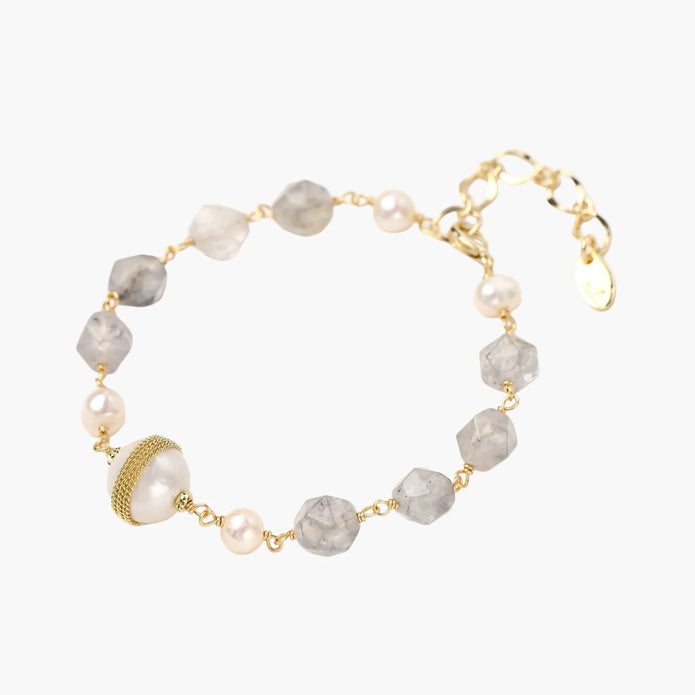 Bracelet with cloudy quartz beads, freshwater pearls, and gold-wrapped baroque pearl centerpiece on white background.