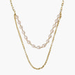 Layered gold chain necklace with organic baroque freshwater pearls and adjustable length on cream background