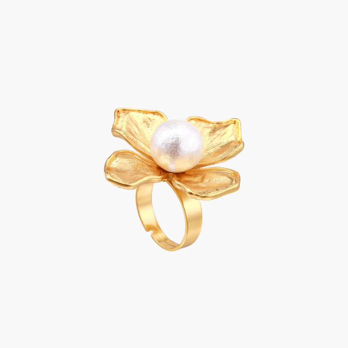 Gold-plated flower ring with textured petals and white cotton pearl center on cream background