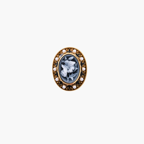 Gold-plated ring with oval blue floral cameo, pearl accents, and black enamel detailing on white background.