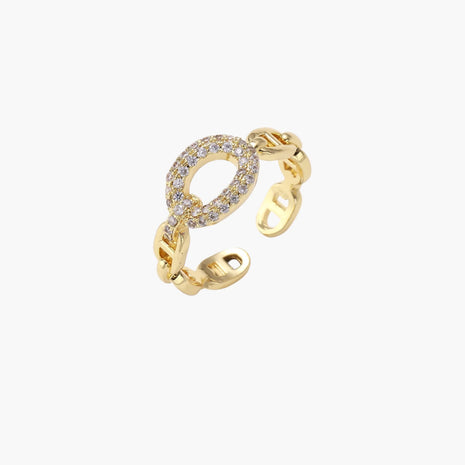 Gold-plated brass chain link ring with one oval CZ-pavé segment on cream background, adjustable cuff style.