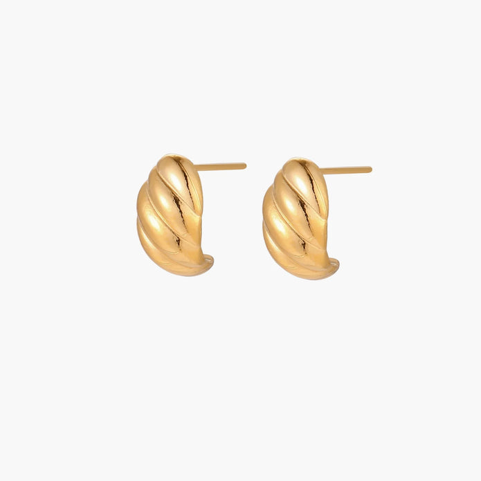 Chunky gold twisted rope huggie hoops with diagonal grooves and high-polish finish on cream background