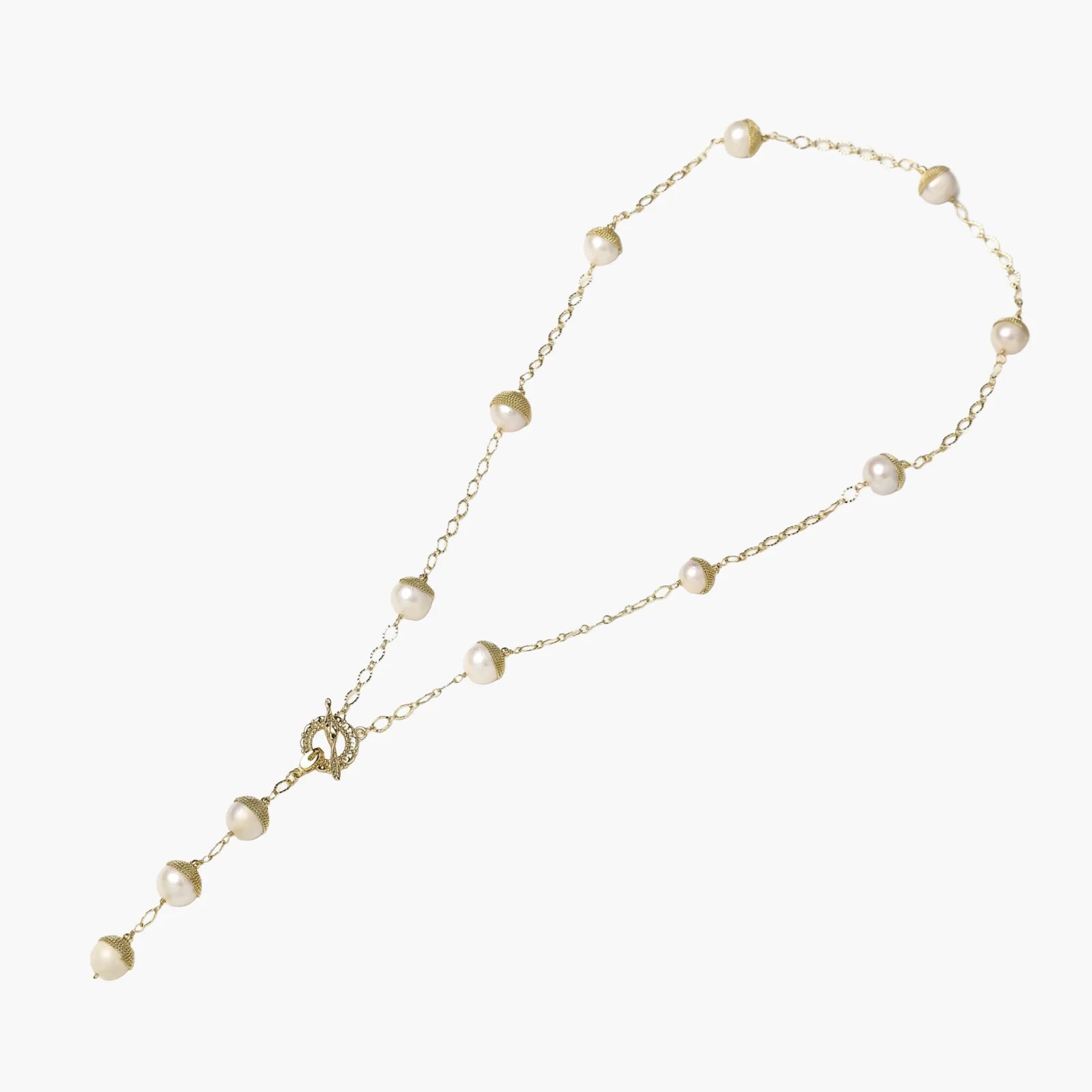 Gold-plated lariat necklace with baroque pearls and textured caps on cream background, showing adjustable Y-shaped design.